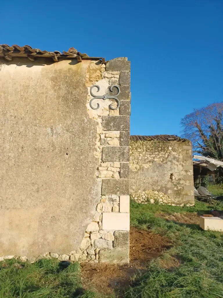 Pose de tirant forgé lors d'une restauration d'un angle de mur en pierre en Gironde.